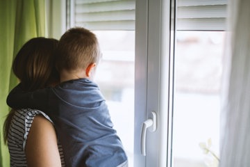 Mother looking out of window with son, thinking about future with MS and family