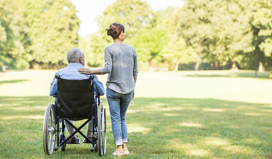 a woman keeps an elderly man in a wheelchair company