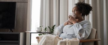 A woman seated with a cup of tea, representing tranquility and the significance of maintaining lung health in COPD awareness.