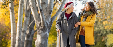 Caregiver going for a walk with her elderly mother, feeling happy as she was able to ask for and find help with caring responsibilities.