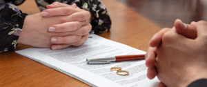 Divorce signature, marriage dissolution document. Wedding ring and agreement on lawyer office table