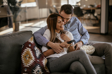 Couple snuggling on couch, having fun despite asthma