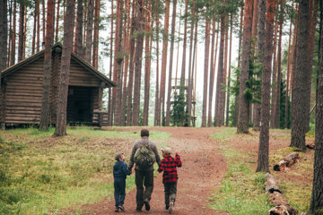 Dad holds hands with children as they walk in the woods