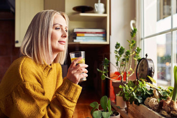 Female heart patient, drinking water, confidently reflecting on new, healthy choices