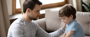 Young caregiver comforts his little brother in the living room