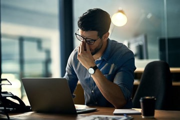 Man stressed and burned out as he works at his laptop