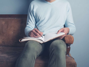 Man writing in journal to track his depression symptoms and any identifiable triggers