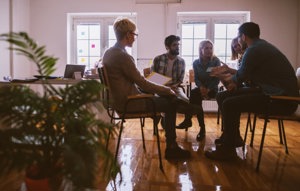 A group of young adults sitting in a room and sharing their mental health stories and experiences.