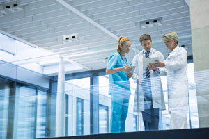 Three doctors comparing notes at the respiratory ward in a hospital.