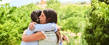 Two women hugging and celebrating their continued friendship