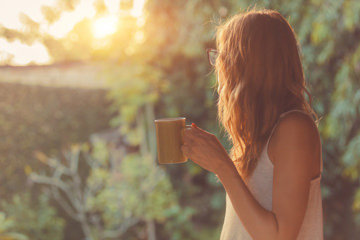 Woman drinking coffee and taking in her garden during self-isolation.