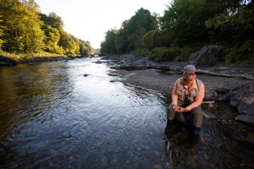 Woman looking thoughtful as she fishes in mountain river