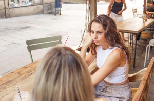 Woman getting bored in coffee shop as her friend dominates the conversation with over-explaining 