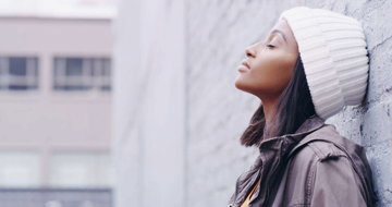 Woman leaning against wall reflecting on the courage and strength dealing with migraine has given her