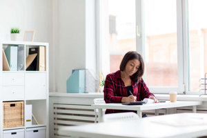 Woman writing in her migraine journal in her study