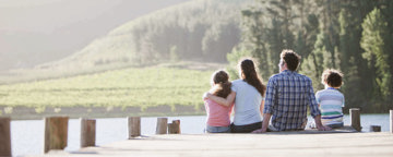 A family sharing a bonding and supportive moment out on a pier by a lakeside