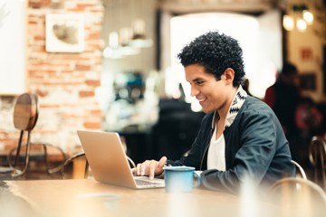 Man smiling as he works on his laptop computer having learned to focus despite ADHD distractability