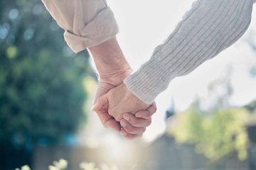 Mature couple united and holding hands, despite the strains of living with Huntington’s disease