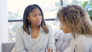 Two African American women holding a conversation in a safe space