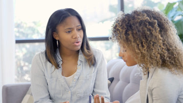 Two African American women holding a conversation in a safe space