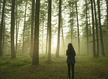 Woman standing alone in the woods