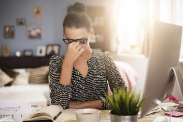 Woman struggling with migraine symptoms as she works from home