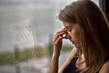 Woman with migraine triggered by barometric pressure shift due to rain